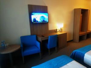 a hotel room with a desk and a tv at Hotel Delicjusz in Trzebaw