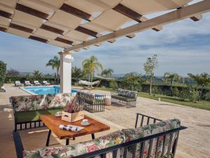 a patio with couches and a table and a pool at Astarte Villas - The Villa in Olive Grove in Lagópodhon