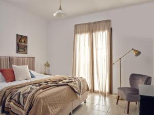 a bedroom with a bed and a chair and a window at Astarte Villas - The Villa in Olive Grove in Lagópodhon
