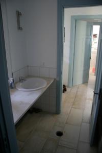 een badkamer met een witte wastafel en een tegelvloer bij Irini’s house in Chios