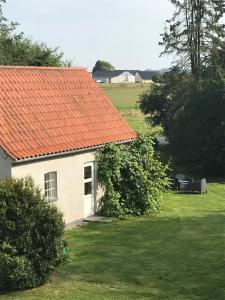 an orange roofed house with a bench in a yard at Landlig idyl - direkte til golfbane in Slagelse