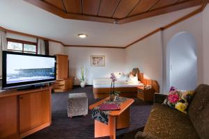 a living room with a large television and a couch at Hotel Gabriela in Serfaus