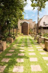 a walkway with grass and stones in front of a building at Shingwedzi Hotel in Benoni