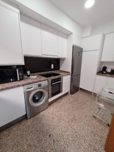 cocina con armarios blancos y lavadora en Dos Torres Ático Dúplex - Céntrico con Vistas a la Ciudad, en Zaragoza