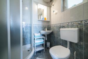La salle de bains est pourvue de toilettes, d'un lavabo et d'une douche. dans l'établissement Apartments Divna, à Baška Voda