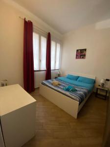 ヌーオロにあるLa casa di saraのベッドルーム1室(青いシーツと赤いカーテンのベッド1台付)