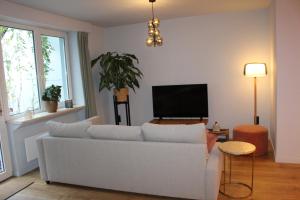 a living room with a white couch and a flat screen tv at Maison Drappier in Ghent