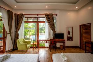 Schlafzimmer mit einem Bett, einem Schreibtisch und einem Fenster in der Unterkunft Mai Binh Phuong Bungalow in Phu Quoc