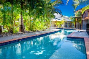 a swimming pool with palm trees next to a building at Edge on Beaches in Agnes Water