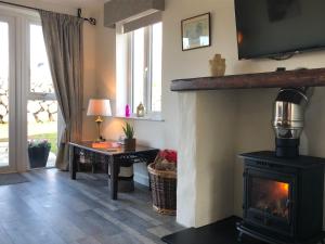 a living room with a fireplace with a table and a desk at Bracken Cottage in Ballymartin