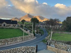 a winding road in a village with mountains in the background at Bracken Cottage in Ballymartin