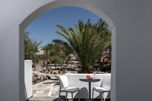 einen Torbogen, der auf eine Terrasse mit einem Tisch und Stühlen führt in der Unterkunft Rivari Santorini Hotel in Kamari