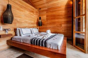 ein Schlafzimmer mit einem Bett in einer Holzwand in der Unterkunft Sea View Clay House in Hiriketiya