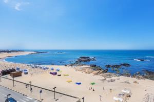 uma praia com cadeiras e guarda-sóis e o oceano em Povoa Sunset Views na Póvoa do Varzim