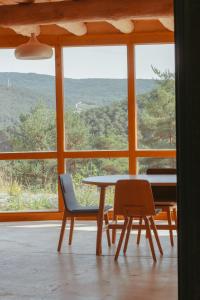 a table and chairs in a room with a large window at Agotzenea - Alojamiento con encanto en un entorno rural in Zubiri