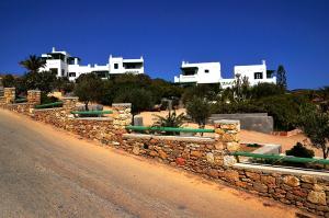 a stone wall next to a road with white buildings at Onar Studios in Koufonisia