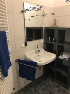 a bathroom with a sink and a mirror and blue towels at Gästehaus Peerhus Dönsel - Deensten in Rehden