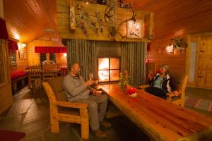 dos personas sentadas en una mesa de madera en una cabaña en Hotel Hetan Majatalo, en Enontekiö