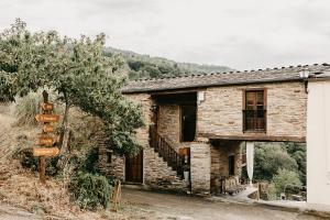 une ancienne maison en pierre avec un panneau en face de celle-ci dans l'établissement Casas de Outeiro, à Samos