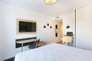 a bedroom with a bed and a desk and a tv at Appart Hotel Odalys City Toulouse Centre Compans Caffarelli in Toulouse