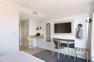 a bedroom with a desk and a tv on a wall at Appart Hotel Odalys City Toulouse Centre Compans Caffarelli in Toulouse