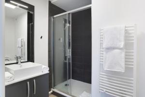 a bathroom with a sink and a glass shower at Appart Hotel Odalys City Toulouse Centre Compans Caffarelli in Toulouse
