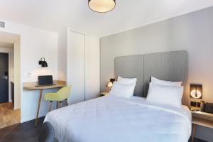 a bedroom with a large white bed and a desk at Appart Hotel Odalys City Toulouse Centre Compans Caffarelli in Toulouse
