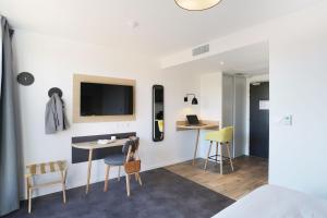 a room with a bed and a table and chairs at Appart Hotel Odalys City Toulouse Centre Compans Caffarelli in Toulouse
