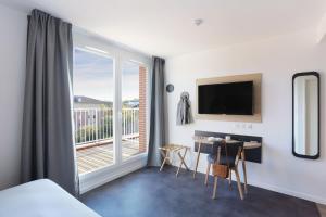 a room with a bed and a desk and a balcony at Appart Hotel Odalys City Toulouse Centre Compans Caffarelli in Toulouse