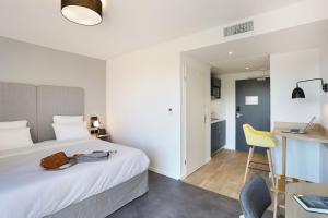 a bedroom with a bed and a desk with a laptop at Appart Hotel Odalys City Toulouse Centre Compans Caffarelli in Toulouse