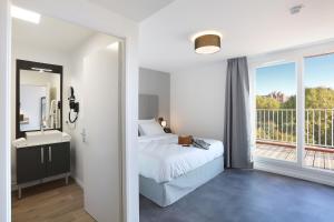 a white bedroom with a bed and a balcony at Appart Hotel Odalys City Toulouse Centre Compans Caffarelli in Toulouse