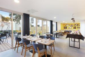 un comedor con mesas, sillas y ventanas en Appart Hotel Odalys City Toulouse Centre Compans Caffarelli, en Toulouse 37 fotos más