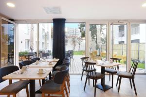 a restaurant with wooden tables and chairs and windows at Appart Hotel Odalys City Toulouse Centre Compans Caffarelli in Toulouse