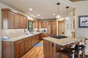 a kitchen with wooden cabinets and a island with bar stools at 3 Tumalo with Wood Burning Fireplace in Sunriver