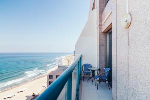 balcone con tavolo, sedie e spiaggia di Almog Haifa Israel Apartments מגדלי חוף הכרמל a Haifa