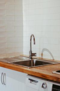 um lavatório de aço inoxidável numa cozinha com azulejos brancos em Agotzenea - Alojamiento con encanto en un entorno rural em Zubiri