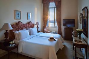a bedroom with a large white bed and a television at Sofitel Winter Palace Luxor in Luxor