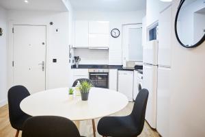 a white kitchen with a white table and chairs at Izpizua Apartment in San Sebastián