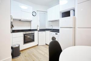 a white kitchen with a refrigerator and a dishwasher at Izpizua Apartment in San Sebastián