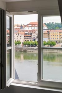 una finestra con vista su un fiume e sugli edifici di limehome Passau Angerstraße a Passavia