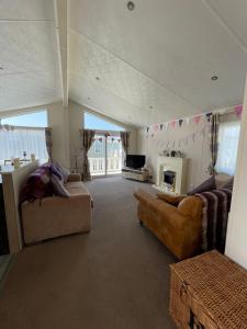 a living room with two couches and a fireplace at Romney Lodge in New Romney