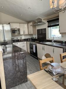 a kitchen with stainless steel appliances and a table at Romney Lodge in New Romney