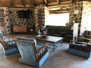 a man sitting in a room with a table and chairs at Bungalow 3 on this world renowned Eco site 40 minutes from Vic Falls Fully catered stay - 1987 in Victoria Falls