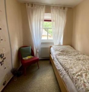 a bedroom with a bed and a chair and a window at Stadthaus Laucha in Laucha
