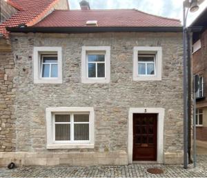 uma casa de tijolos com uma porta castanha e janelas brancas em Stadthaus Laucha em Laucha