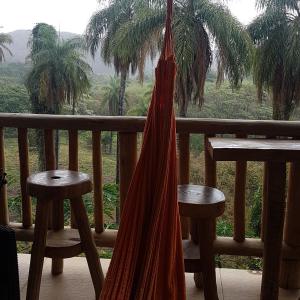 a hammock hanging from a balcony with palm trees at Pousada Sempre Luz in Santana do Riacho