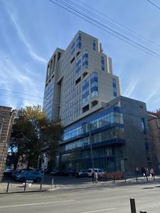 wysoki szklany budynek z samochodami zaparkowanymi przed nim w obiekcie Civilization w mieście Dniepr