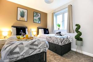 a bedroom with two beds and a window at Luxury House - Sleeps 12 - Smart TVs, Fast Wifi, Garden and Free Parking by Yoko Property in Kempston