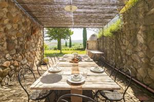 una larga mesa de madera con sillas y una pared de piedra. en Casa del Dottore by VacaVilla, en Celle sul Rigo