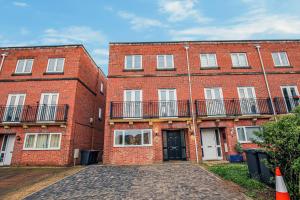 a large red brick building with a driveway at Luxury House - Sleeps 12 - Smart TVs, Fast Wifi, Garden and Free Parking by Yoko Property in Kempston
